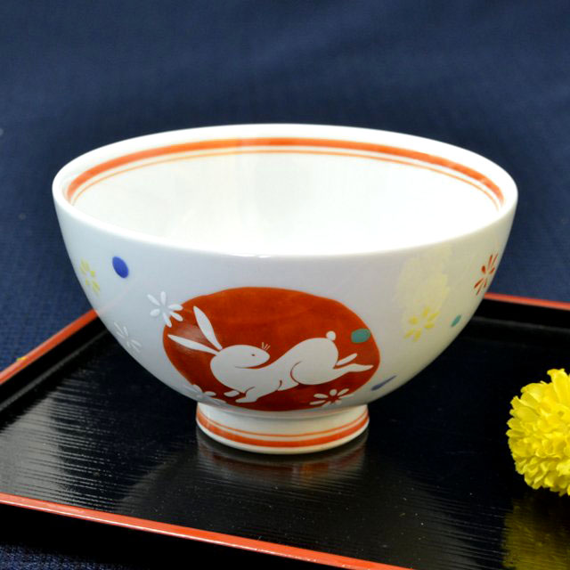かわいらしいうさぎのデザインのご飯茶碗です。飯碗の縁や高台には赤色のラインが巻かれています。大きさは口径11.5cm高さ6.5cmほどあります。少し青みがかった白色の飯碗で、落ち着いた雰囲気になっています。