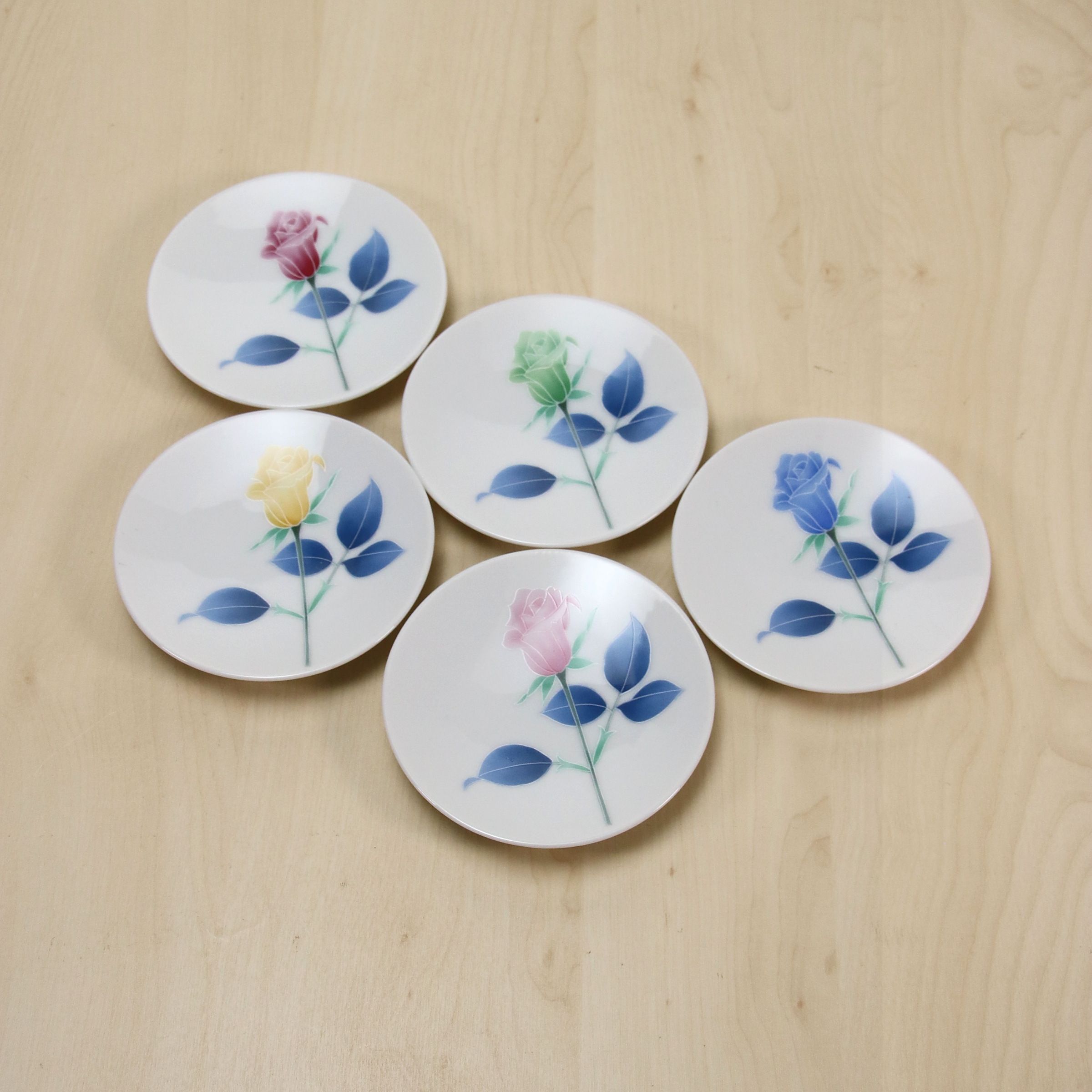 5色の薔薇が小皿に大きくデザインされています。テーブルに並べるだけで華やかになりますね。径が約9cm高さが約1.5cm5枚重ねたときの高さが約5cmです。お皿のは平たい形状で、御一人様分のお漬物をのせるにちょうど良いくらいの大きさです。スプーンレストなどで使ってもおしゃれでいいですね。電子レンジもお使いいただけます。