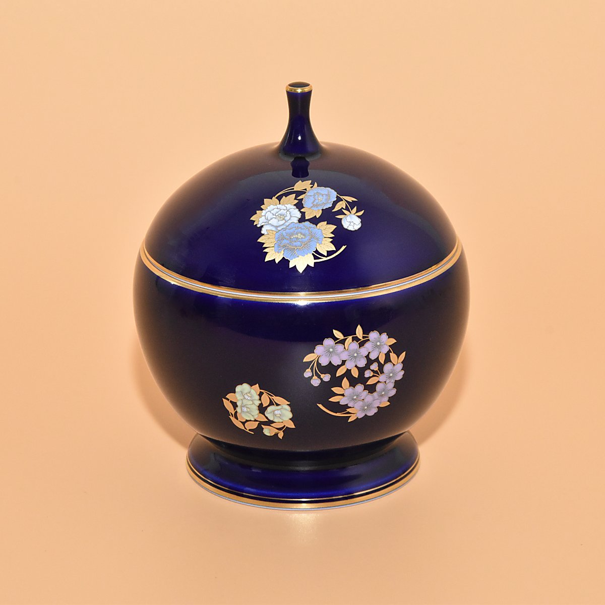 艶やかなルリ色に和のアイテムをお洒落にデザインした、華やかさが際だつ美しいキャンディーポットです。チョコレートやキャンディーなどのおやつや、小物を入れてお使いいただけます。径約12cm 高さ約15cmになります。香蘭社らしいるり色がとても美しく存在感のあるお品です。