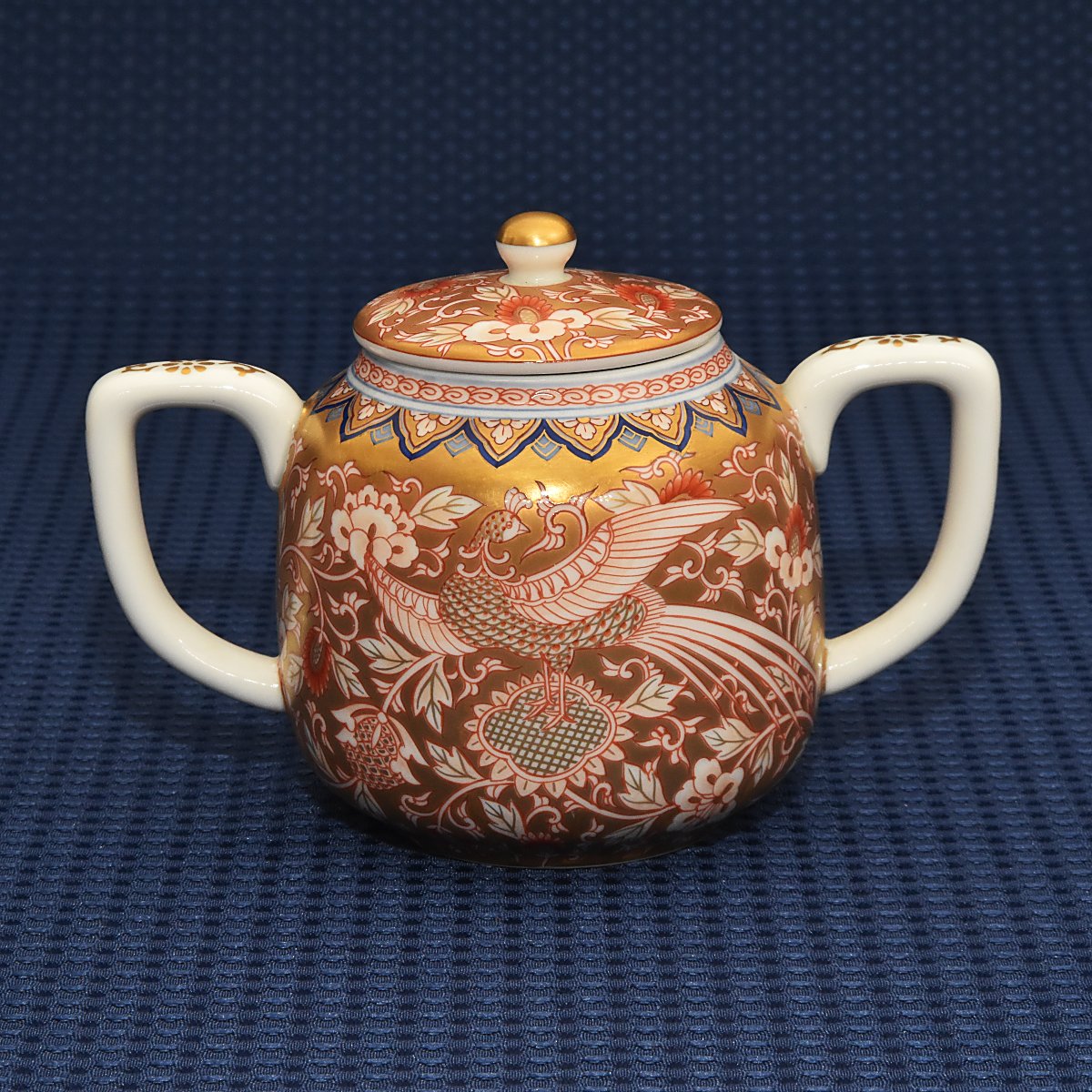 明治初期にデザインされた金襴手鳳凰紋のデザインをモチーフにしたデザインです。繊細で巧妙に描かれた鳳凰と唐草文の周囲を金襴手で埋め尽くし縁を地紋で埋めた豪華絢爛な絵付けです。ワンランク上のティータイムを味わえるオススメのシュガーポットです。
サイズ:胴径9*高11㎝です。
